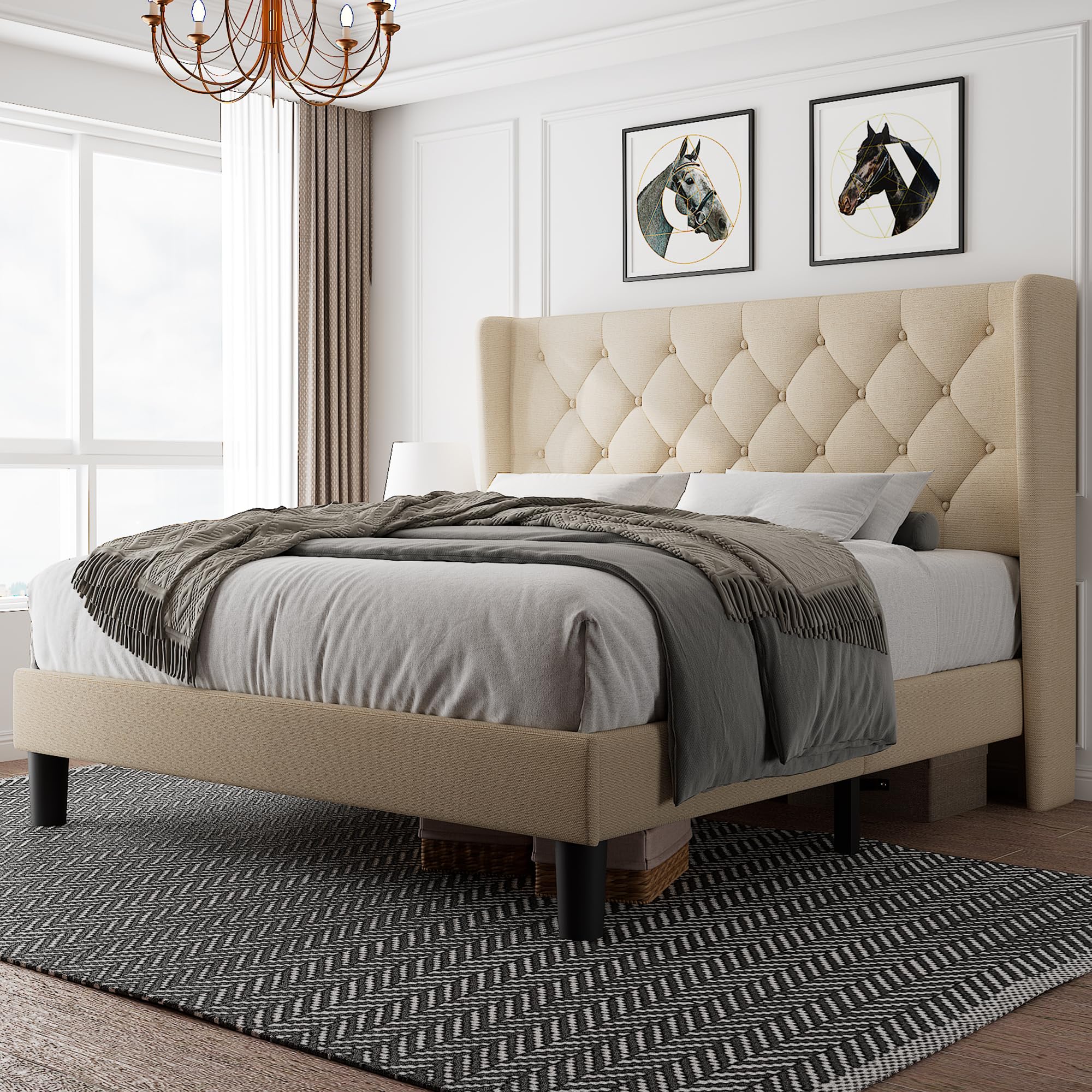 A beige upholstered platform bed frame with a wingback headboard, dressed with a grey bedsheet and a brown blanket, placed in a room with decor.