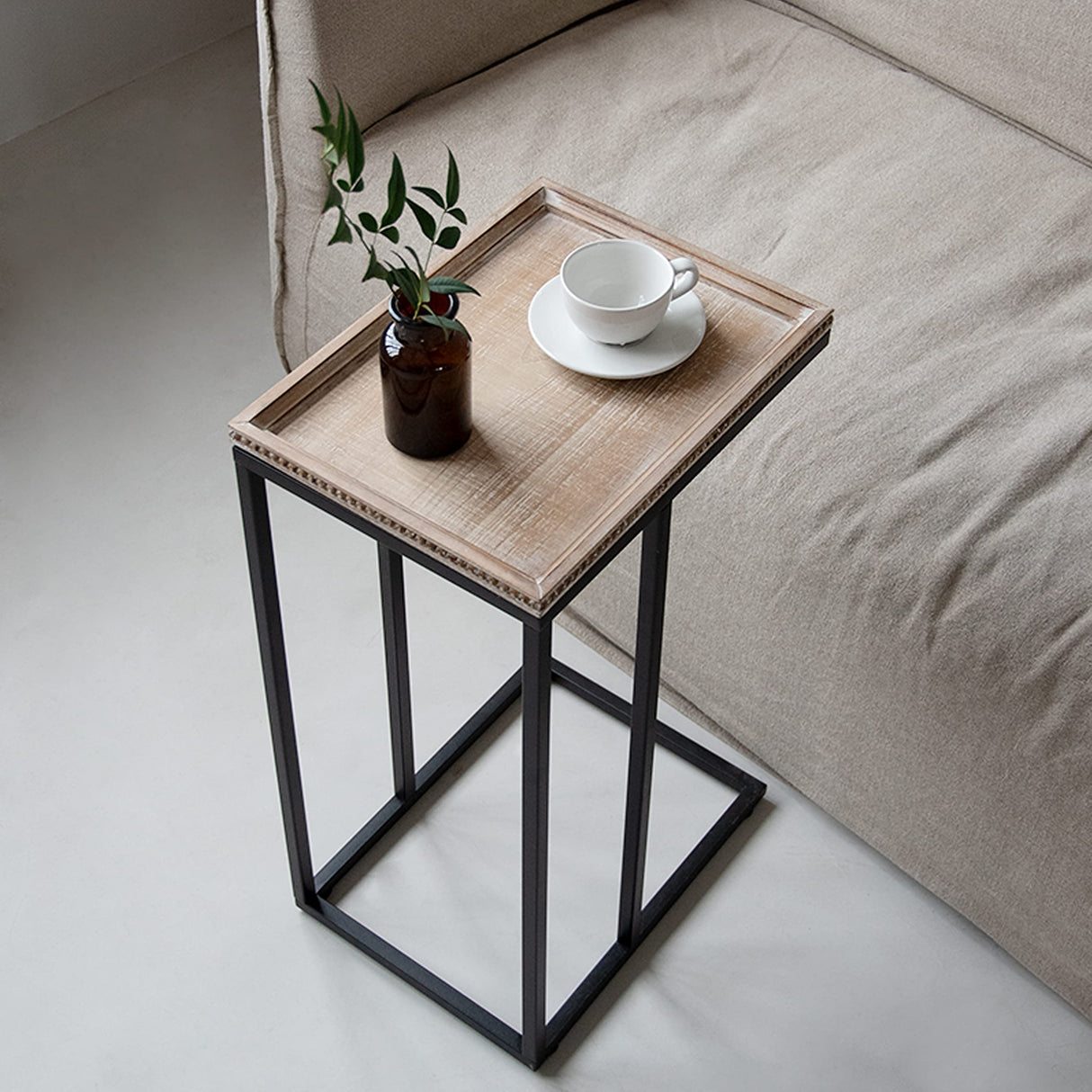 Side table placed next to a couch with a coffee mug and book.