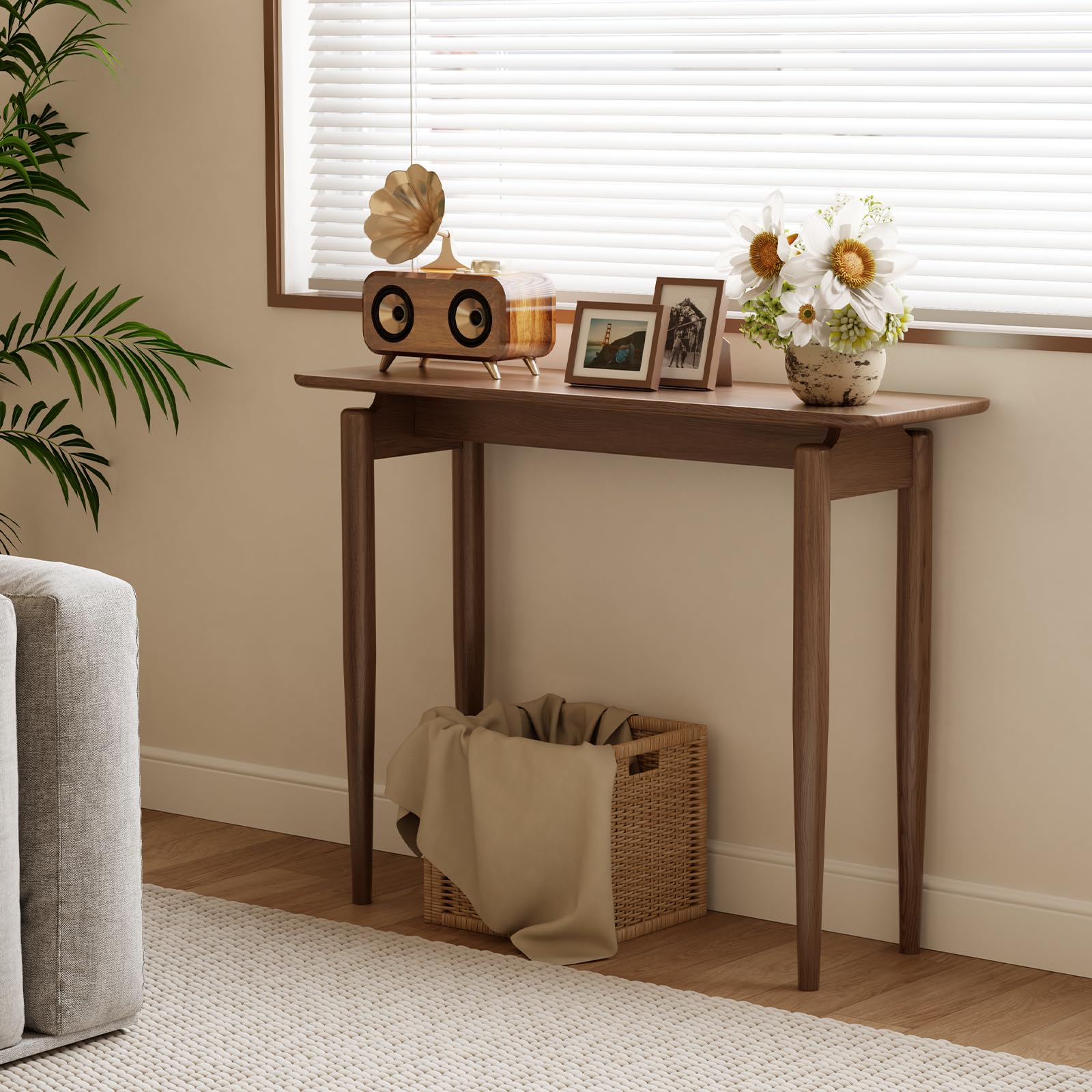 Walnut console table with decorative flowers and photo frames near window